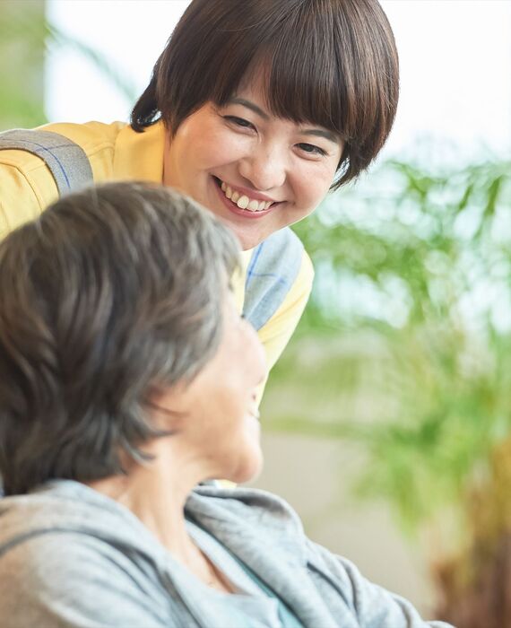車いすの女性に声をかける女性ヘルパー